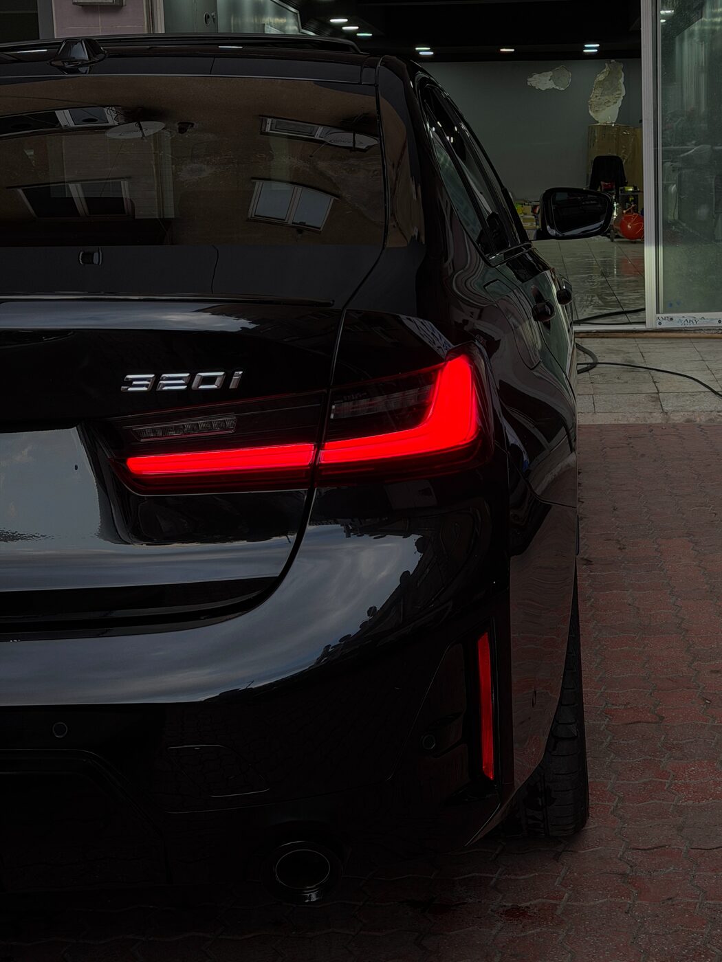 Stüdyoda, arka stopları yanan siyah BMW 320i
